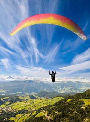 Paraglider flying over mountains in summer day